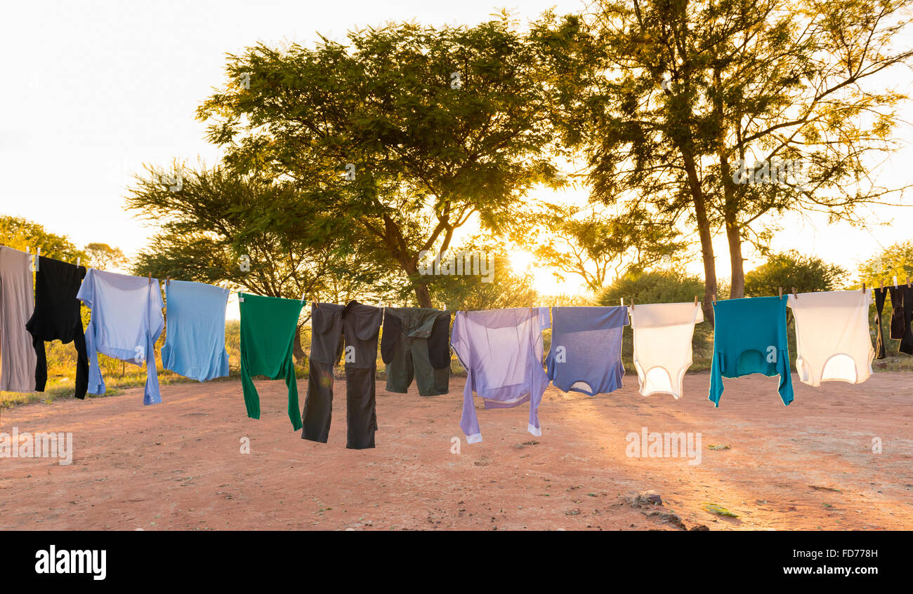 E Mens womens asciugabiancheria esterna sulla linea di abbigliamento con pioli e sun streaming in dietro Foto Stock