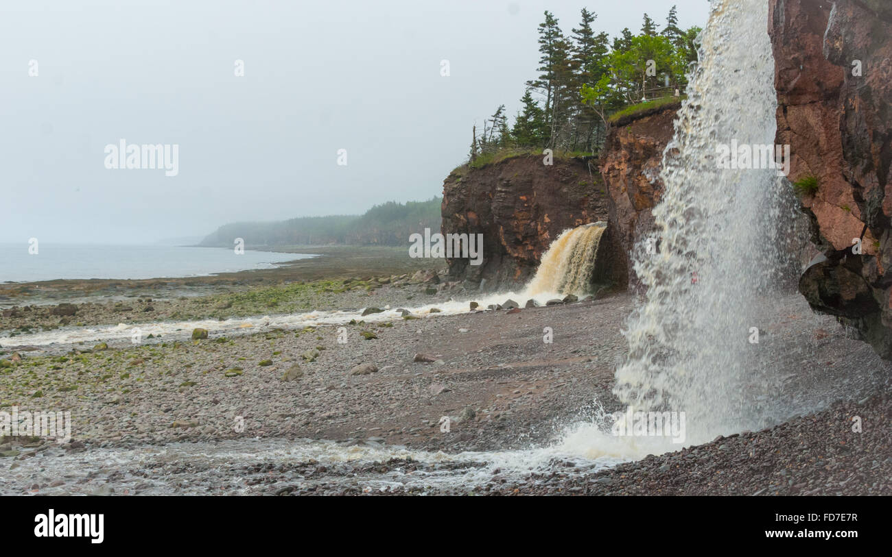 Primavera Nova Scotia costa in giugno. Cascate da scogliera rocciosa sulla spiaggia di ciottoli. Foto Stock