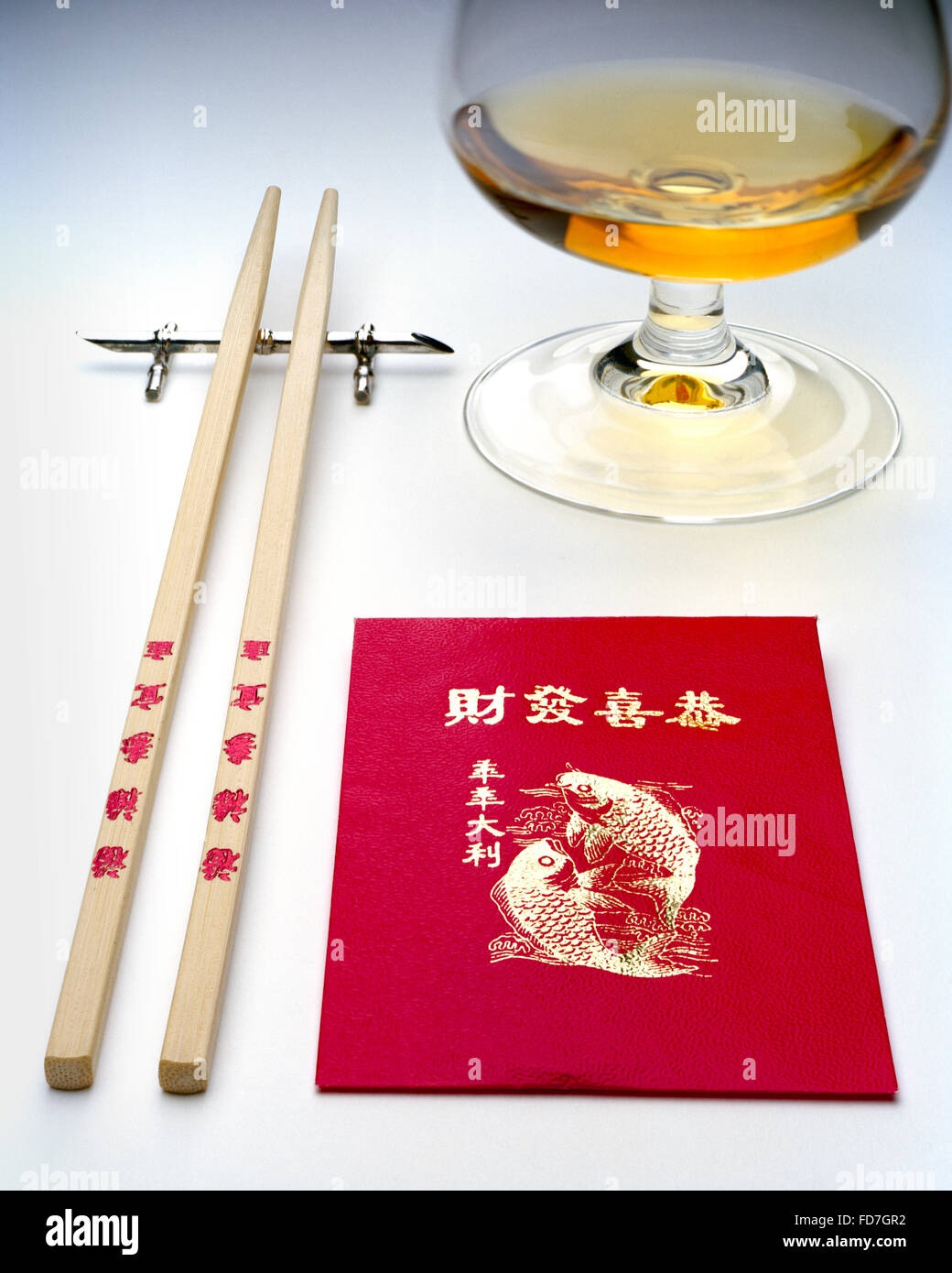 Kung Hei Fat Choi in caratteri oro su rosso Lucky Money busta con bacchette e bicchiere di brandy Foto Stock