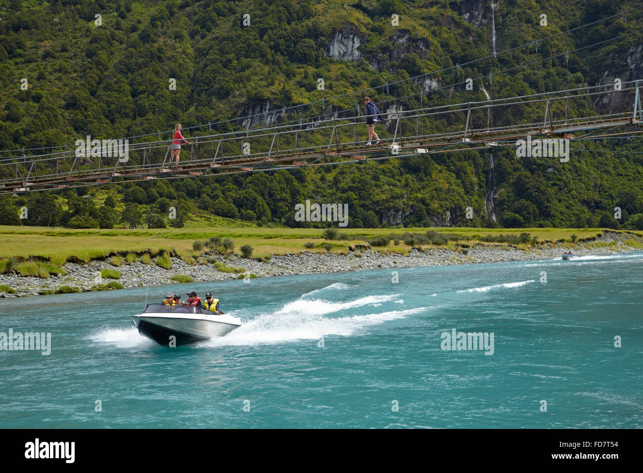 Jet Boat e persone sulla sospensione ponte sul fiume Matukituki ramo Ovest, Matukituki Valley, vicino a Wanaka, Otago, Isola del Sud, Foto Stock