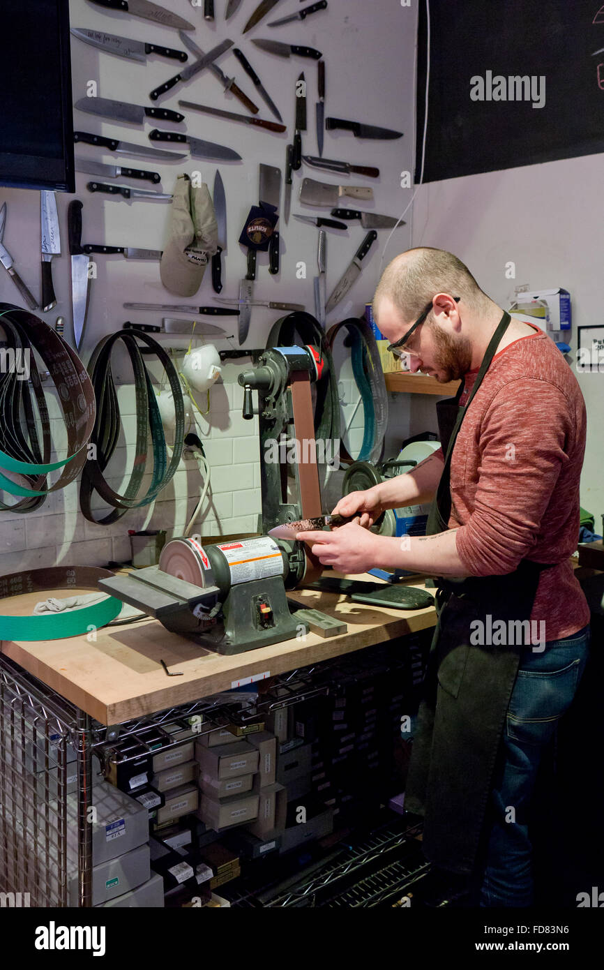 Uomo di affilatura dei coltelli da cucina sulla levigatrice a nastro - USA  Foto stock - Alamy