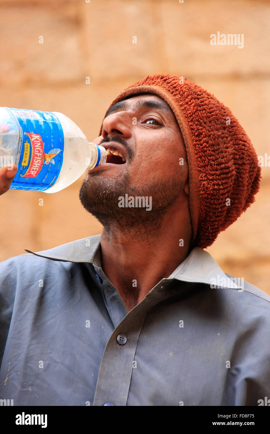 Uomo indiano di bere acqua da una bottiglia a Jaisalmer fort, Rajasthan, India Foto Stock