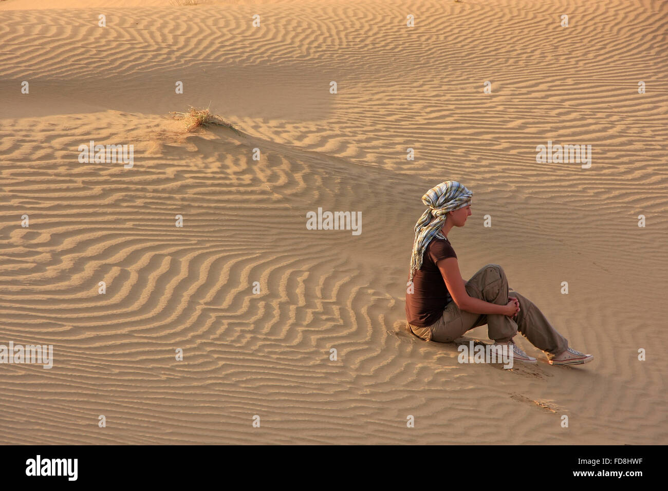 Giovane donna seduta sulle dune del deserto di Thar, Jaisalmer, Rajasthan, India Foto Stock