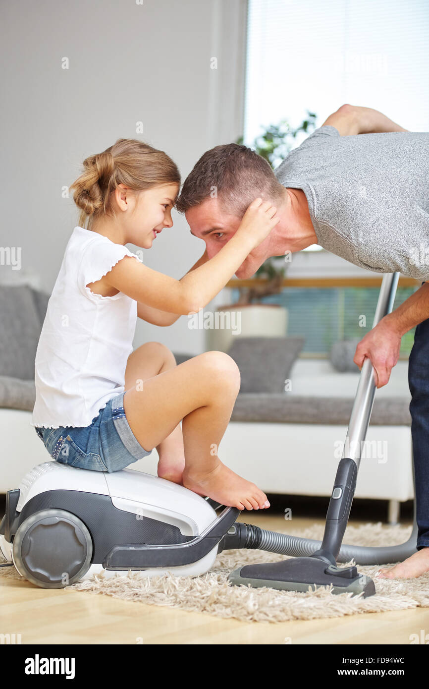 Padre e figlia si divertono con aspirapolvere mentre la pulizia a casa Foto Stock