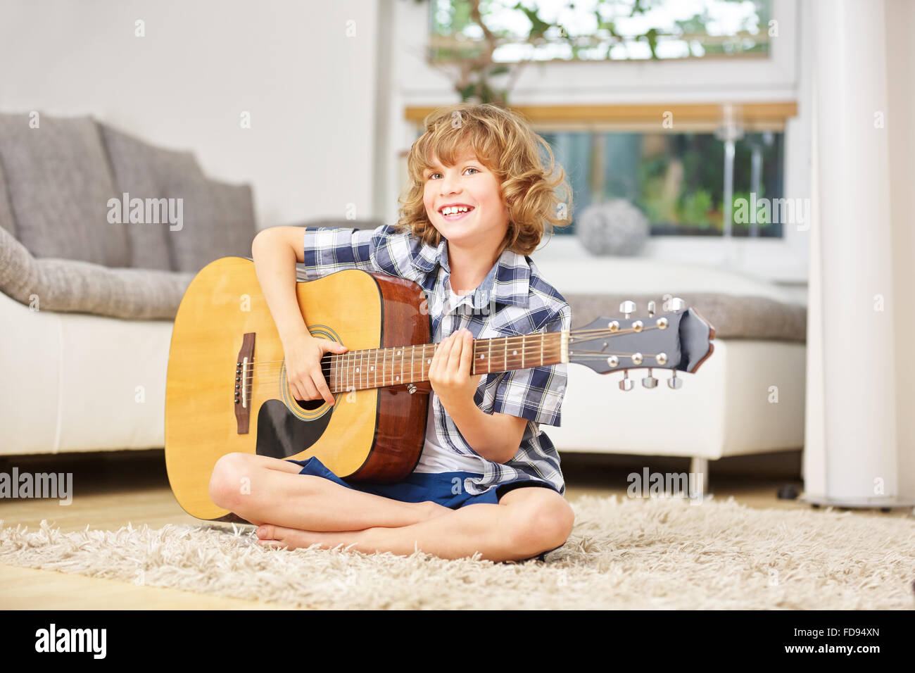 Felice ragazzo rendendo la musica suonare la chitarra a casa Foto Stock