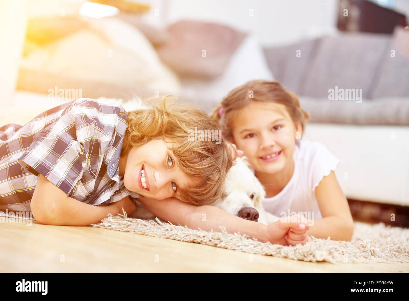Due felici i bambini giocano in casa con un Golden Retriever cane Foto Stock