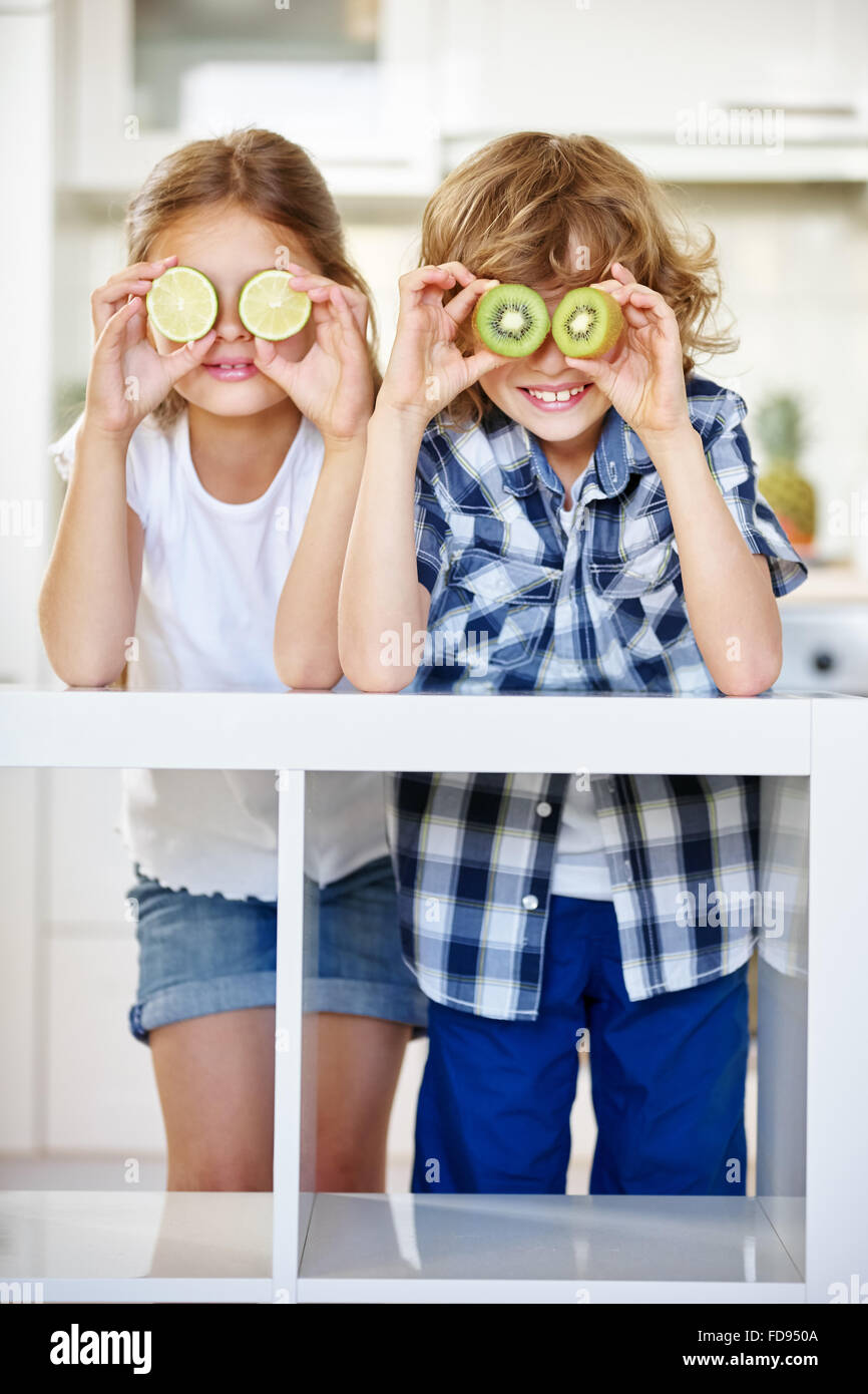 Un ragazzo e una ragazza di nascondersi dietro i frutti in cucina Foto Stock