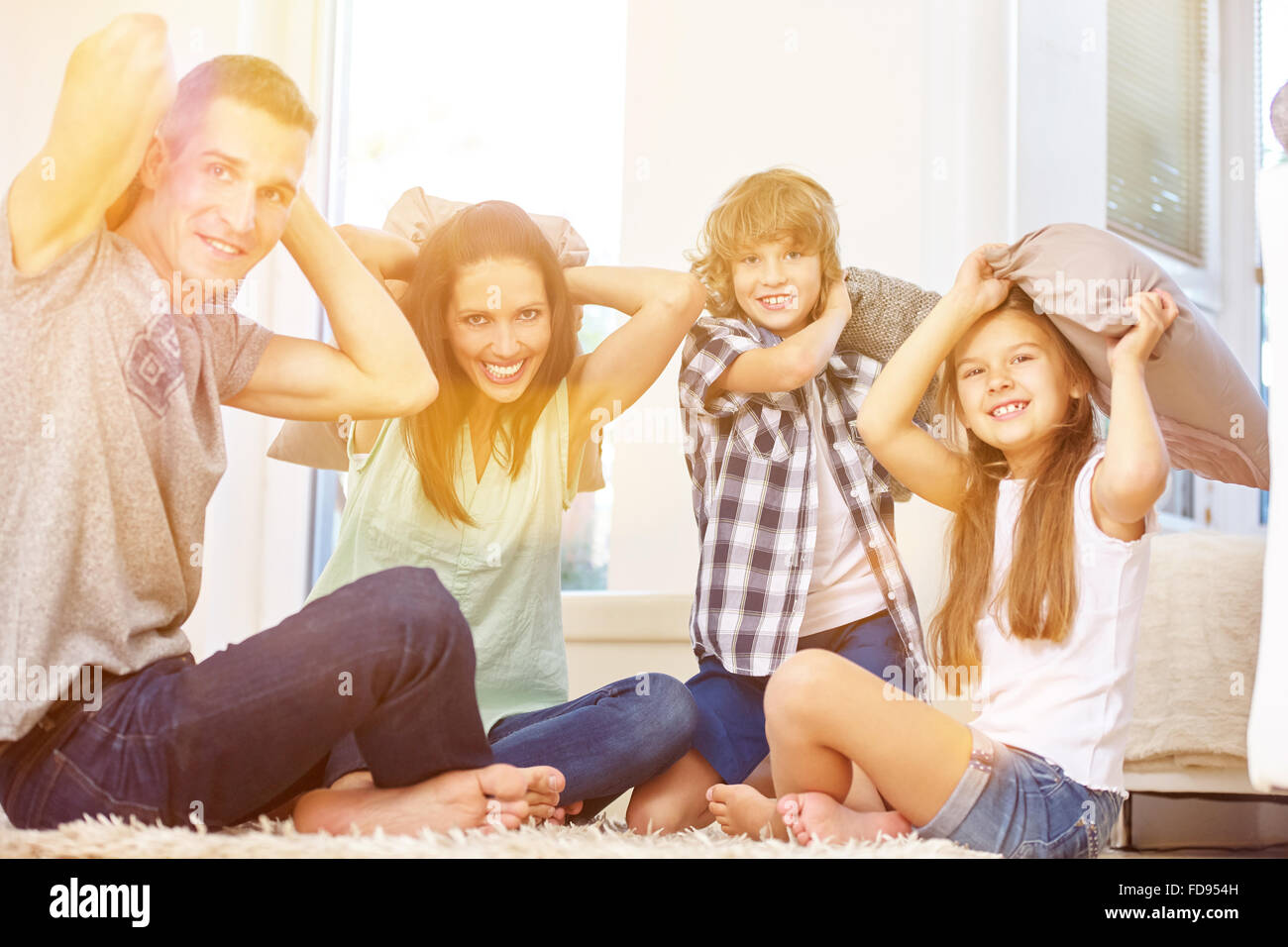 La famiglia felice e i bambini aventi cuscino lotta in casa nel salotto Foto Stock