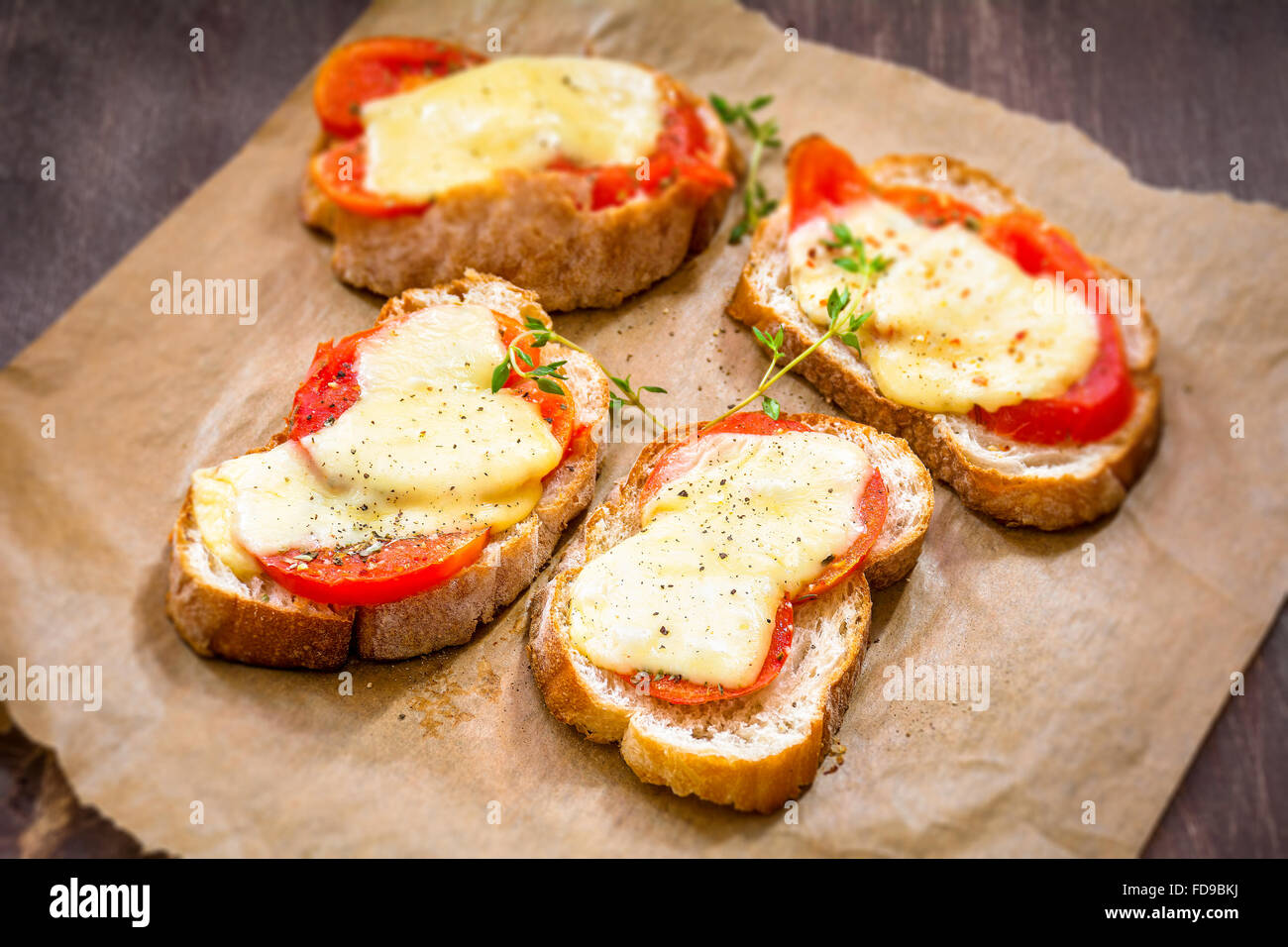 Antipasti: bruschetta con pomodoro, formaggio e timo su carta pergamena Foto Stock