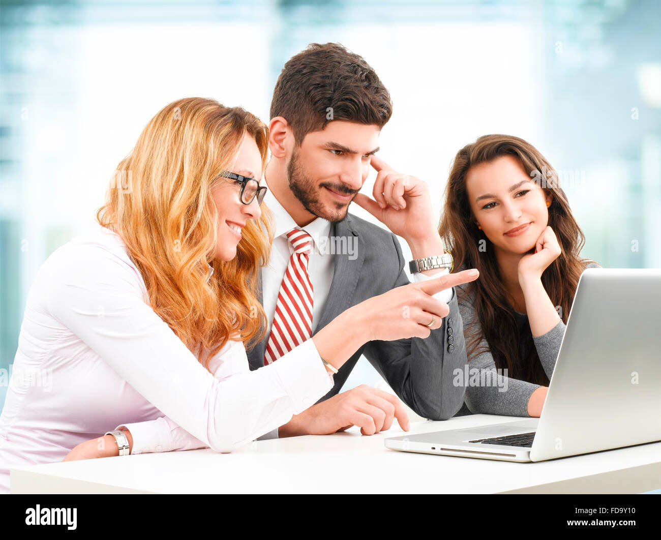 Il team di Business analizzando i dati finanziari sul computer portatile mentre è seduto in ufficio. Foto Stock