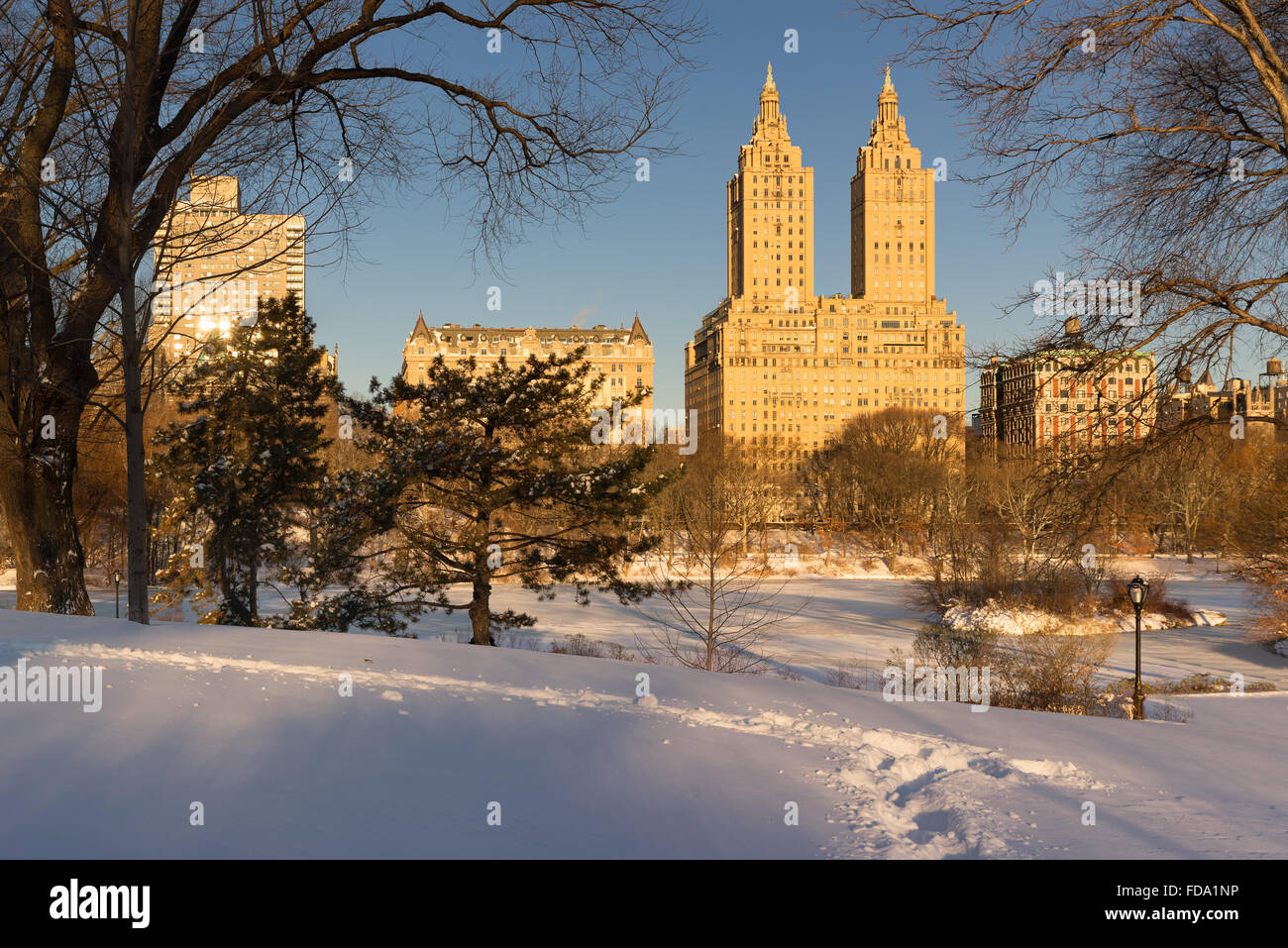 Alba sul lago ghiacciato a Central Park dopo una tempesta di neve in inverno con vista sulla Upper West Side di edifici. Manhattan, New York Foto Stock