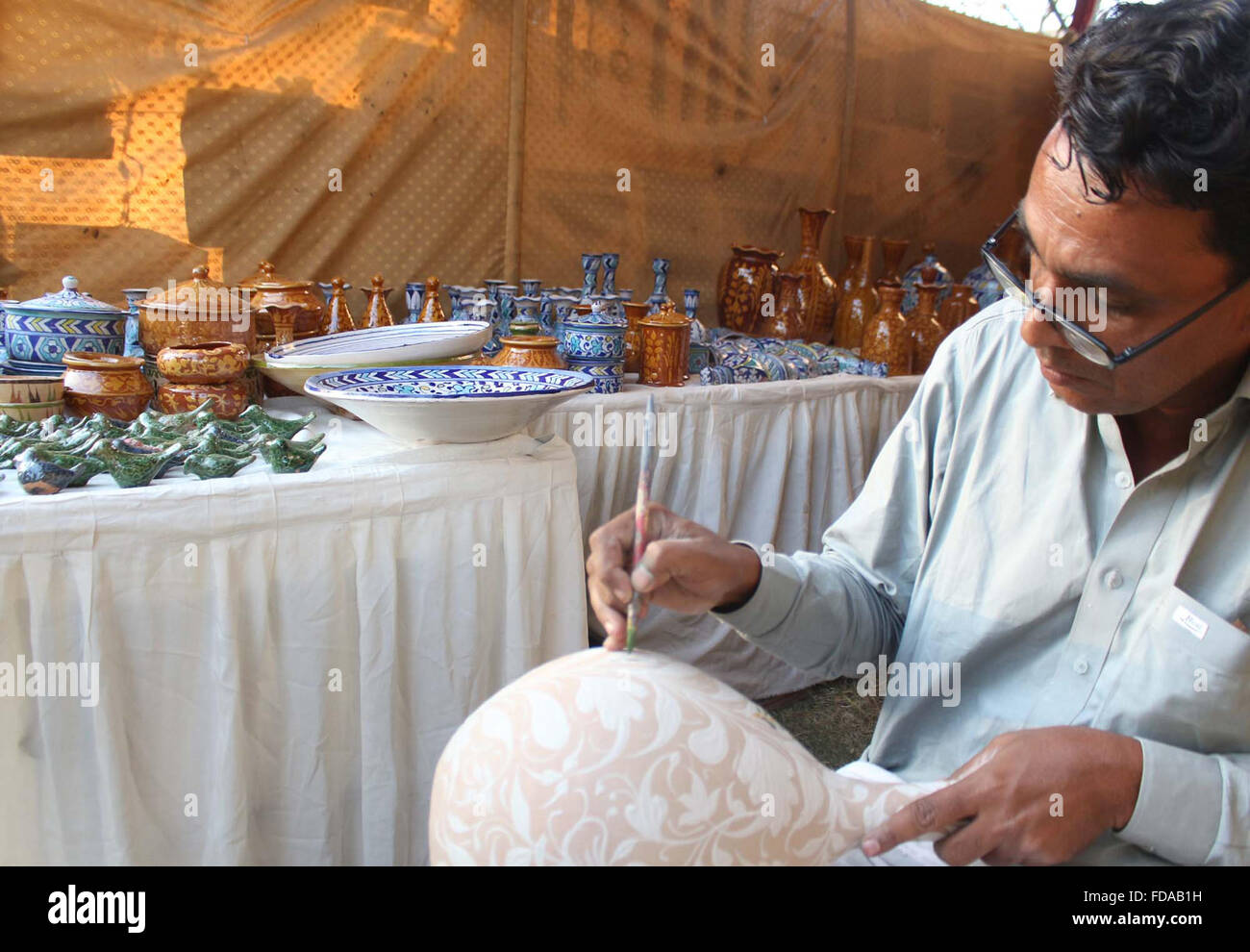 Artigiano occupato in pittura la pentola durante Sindh festival culturali tenutosi presso il Museo Nazionale a Karachi il Venerdì, 29 gennaio 2016. Foto Stock