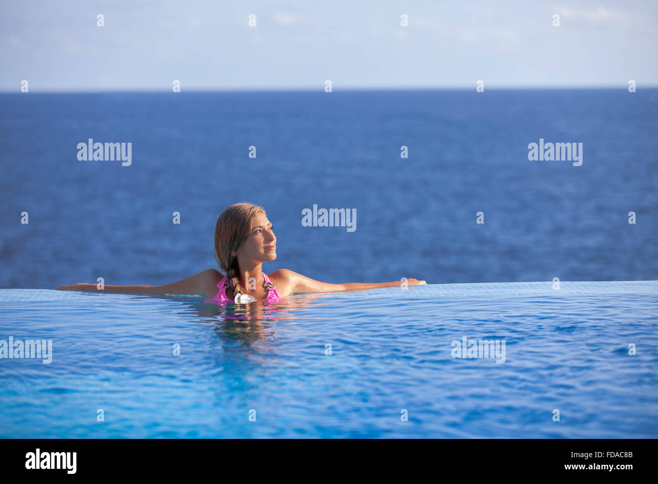 Donna felice rilassante nella piscina a sfioro in estate Foto Stock