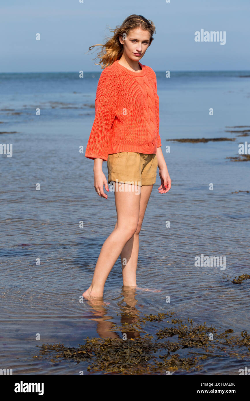 Ritratto di una giovane e bella donna presso la spiaggia. Guarda la fotocamera e di indossare un abbigliamento informale mentre in piedi la Foto Stock