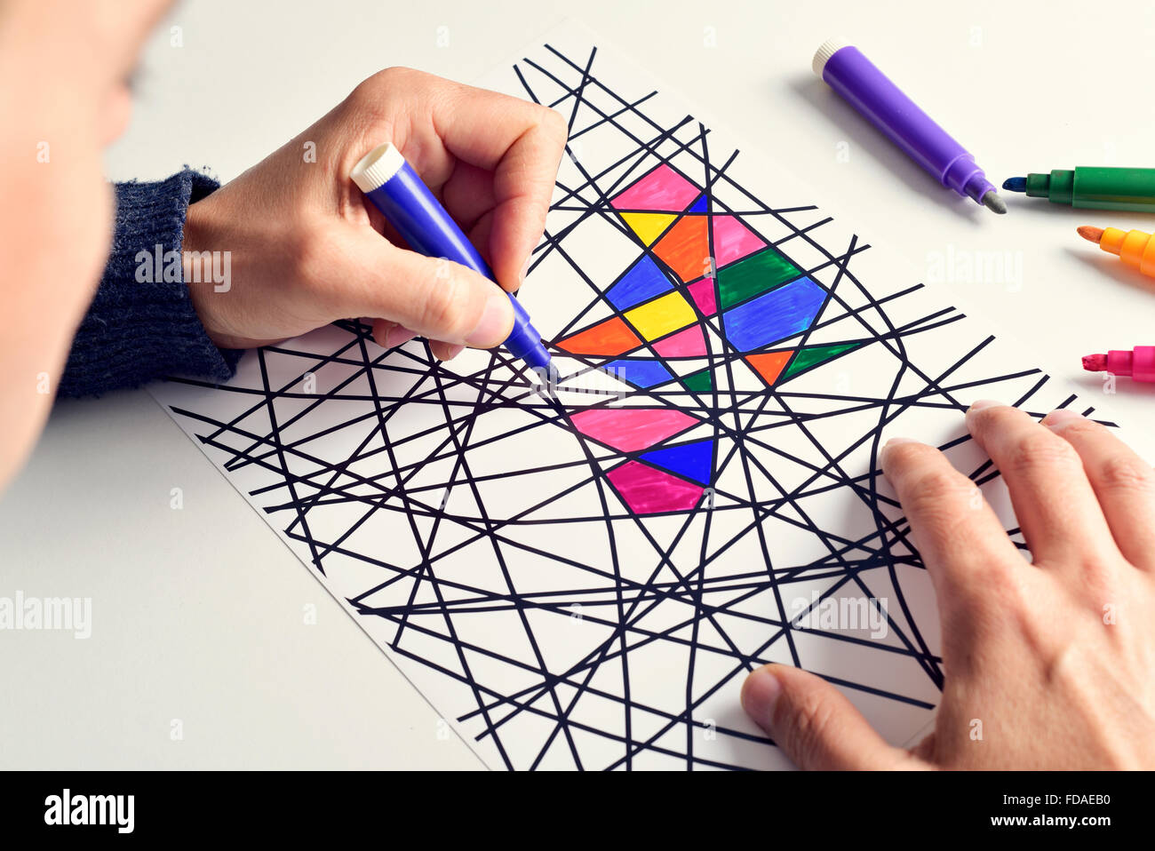 Primo piano di un giovane uomo di colorare un disegno astratto, progettato  da me, con pennarelli di diversi colori Foto stock - Alamy