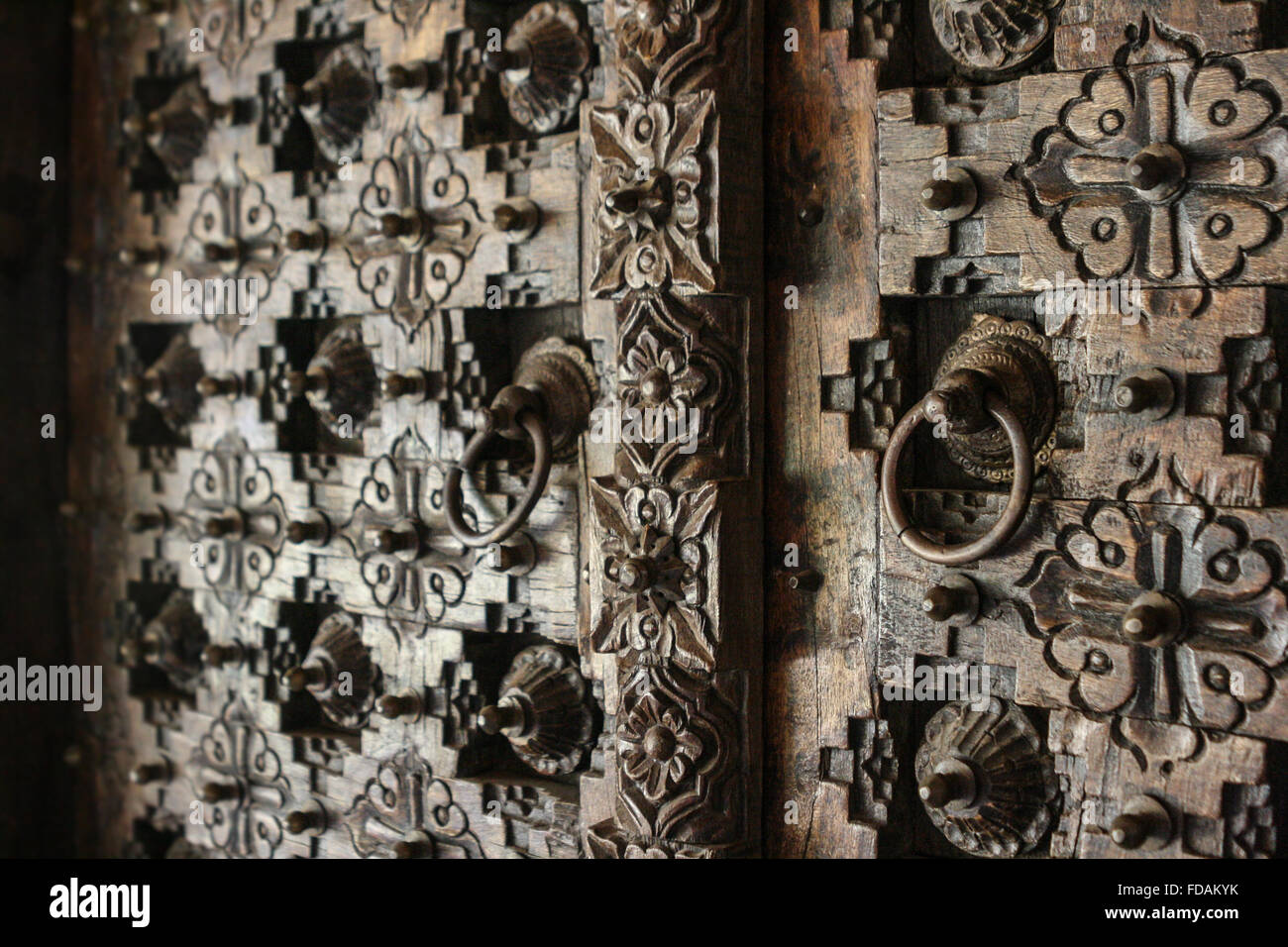 Full frame fino in prossimità di un pesantemente inciso scolpito in legno Porte anteriori con circolare le maniglie della porta tira in India Foto Stock