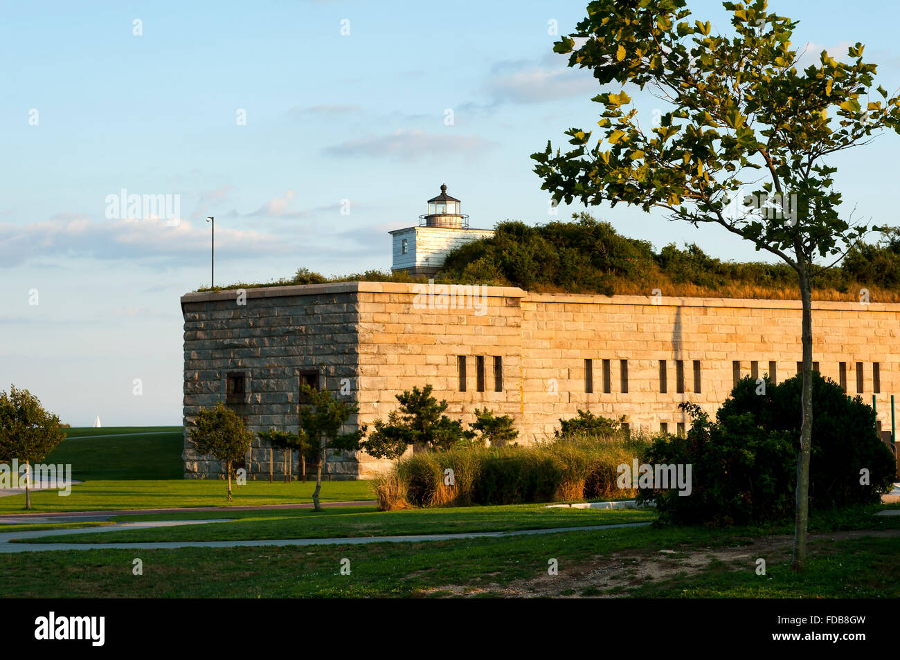 La vecchia torre del faro di Clark punto luce si siede sulla cima di pietra costruiti Fort Taber come il sole tramonta, illuminando il parco in un bagliore dorato. Foto Stock