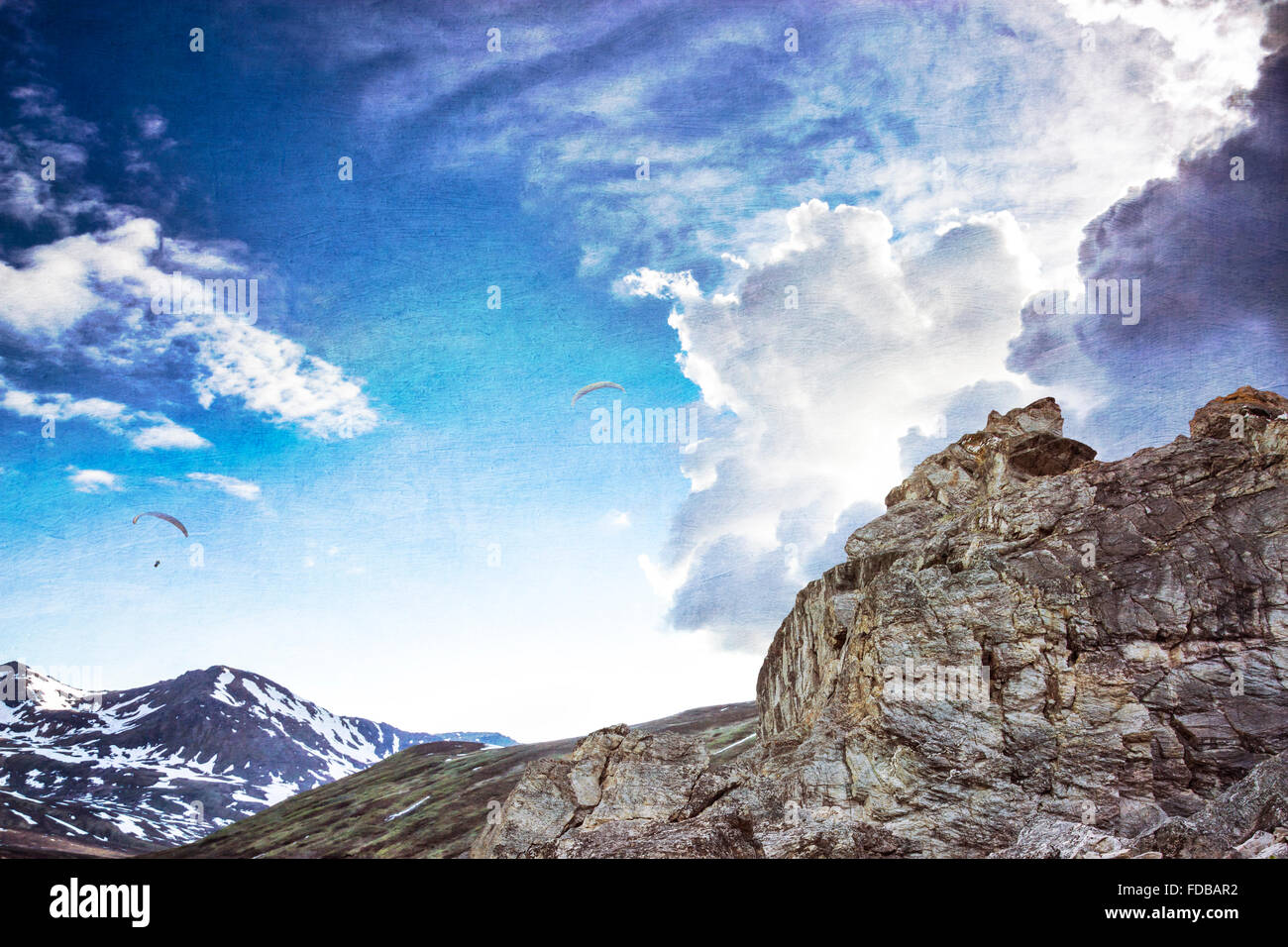 Deltaplano volare in nuvole drammatico al di sopra dei picchi di montagna con le texture aggiunto per un look di fantasia. Foto Stock