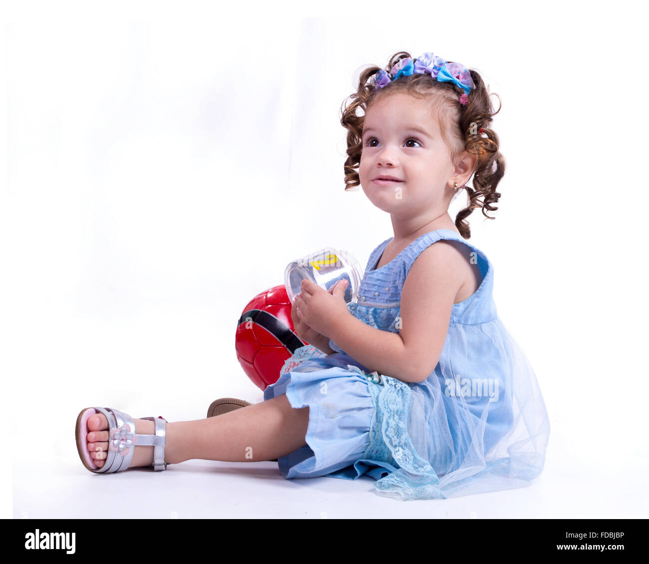 Ragazza seduta con una manopola in mano e una palla rossa dietro di lei Foto Stock