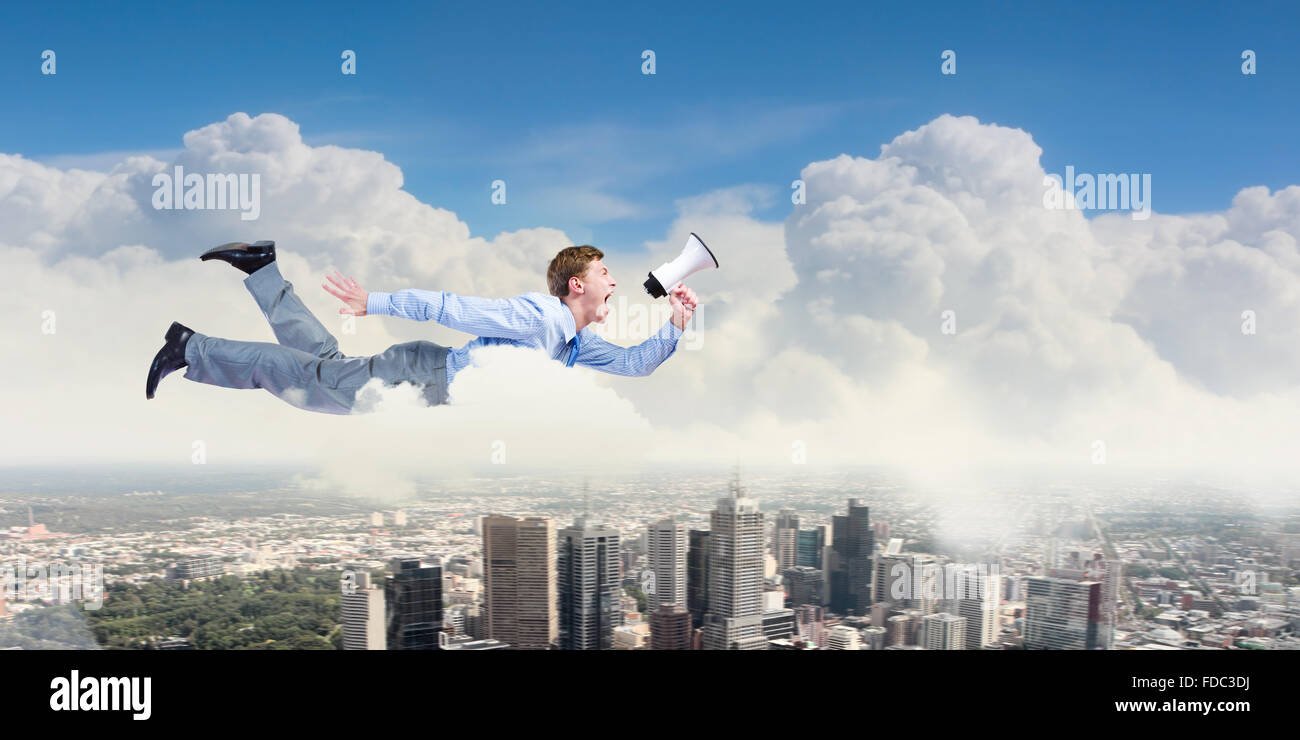 Giovane imprenditore con megafono volare alto nel cielo Foto Stock