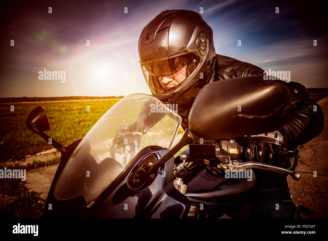 Biker in casco e giacca di pelle racing su strada. Filtro applicato in post-produzione. Foto Stock Biker in casco e giacca di pelle racing su strada. Filtro applicato in post-produzione. Foto Stock