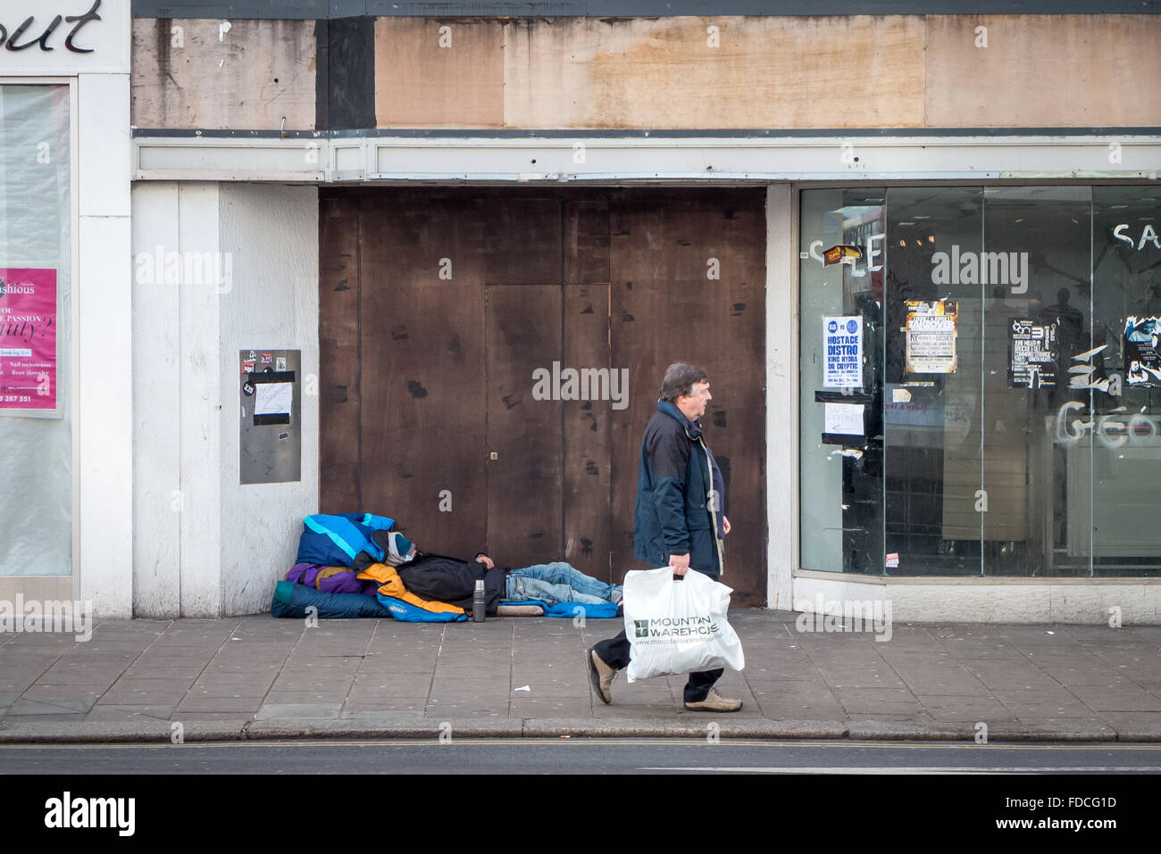 Saliti a bordo-fino ai negozi e una persona senza dimora su Western Road, la strada principale dello shopping nel centro città di Brighton. Foto Stock