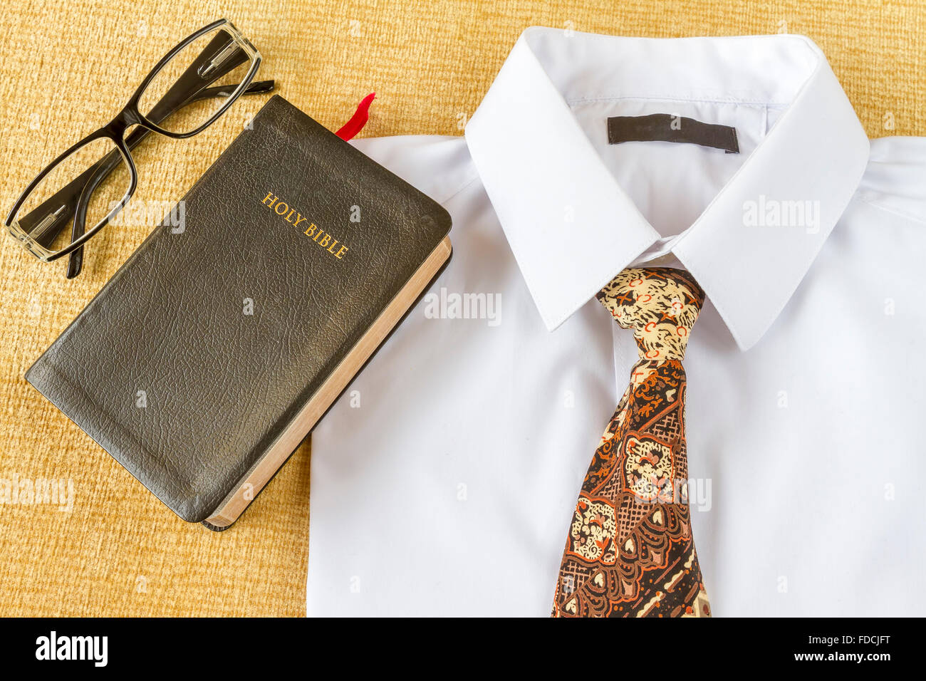 Pastore vestiti e Sacra Bibbia con gli occhiali a casa. Il cristianesimo o andare in chiesa concetto. Foto Stock