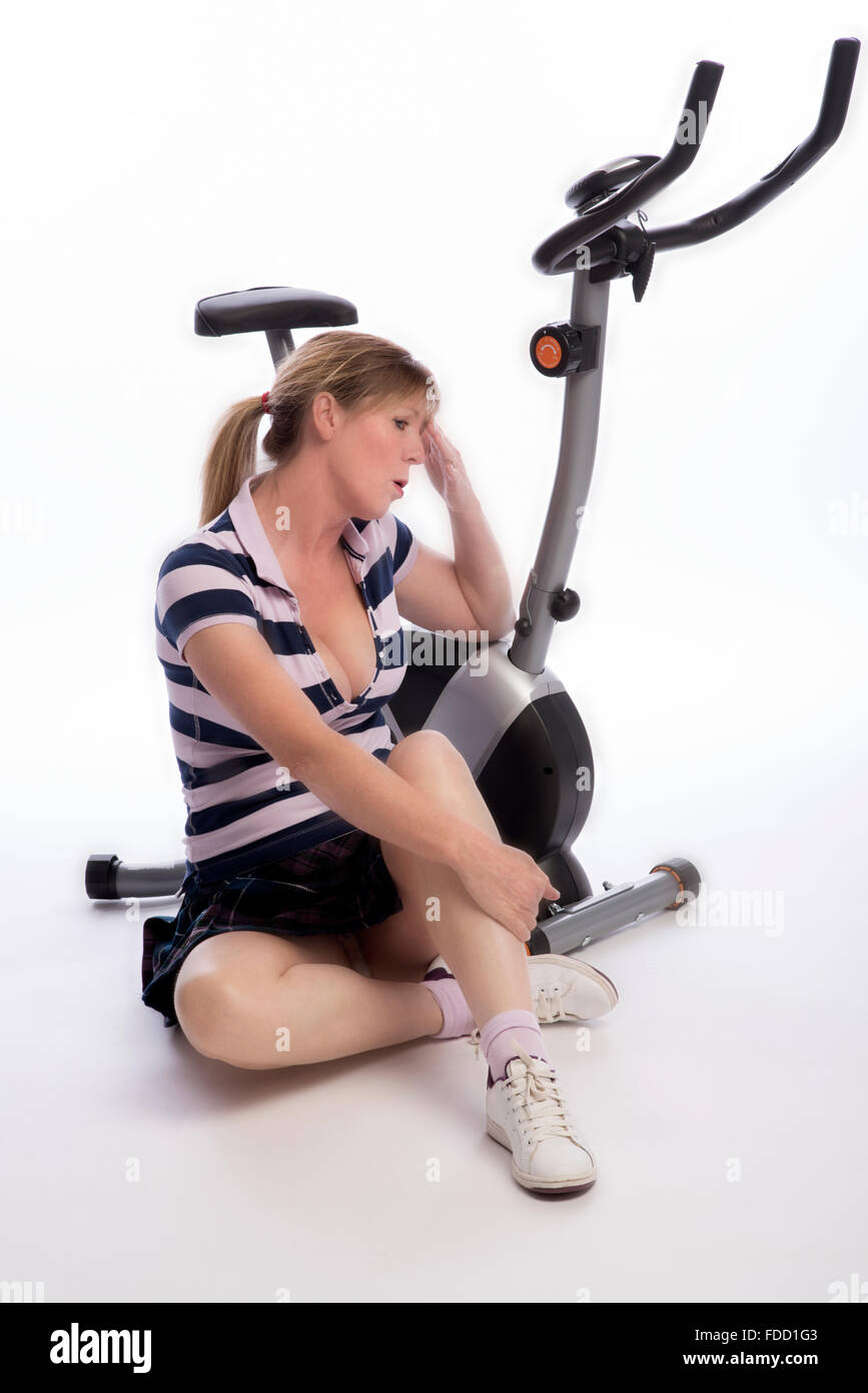 Esaurito donna con la sua mano sulla testa appoggiata sul suo cyclette Foto Stock