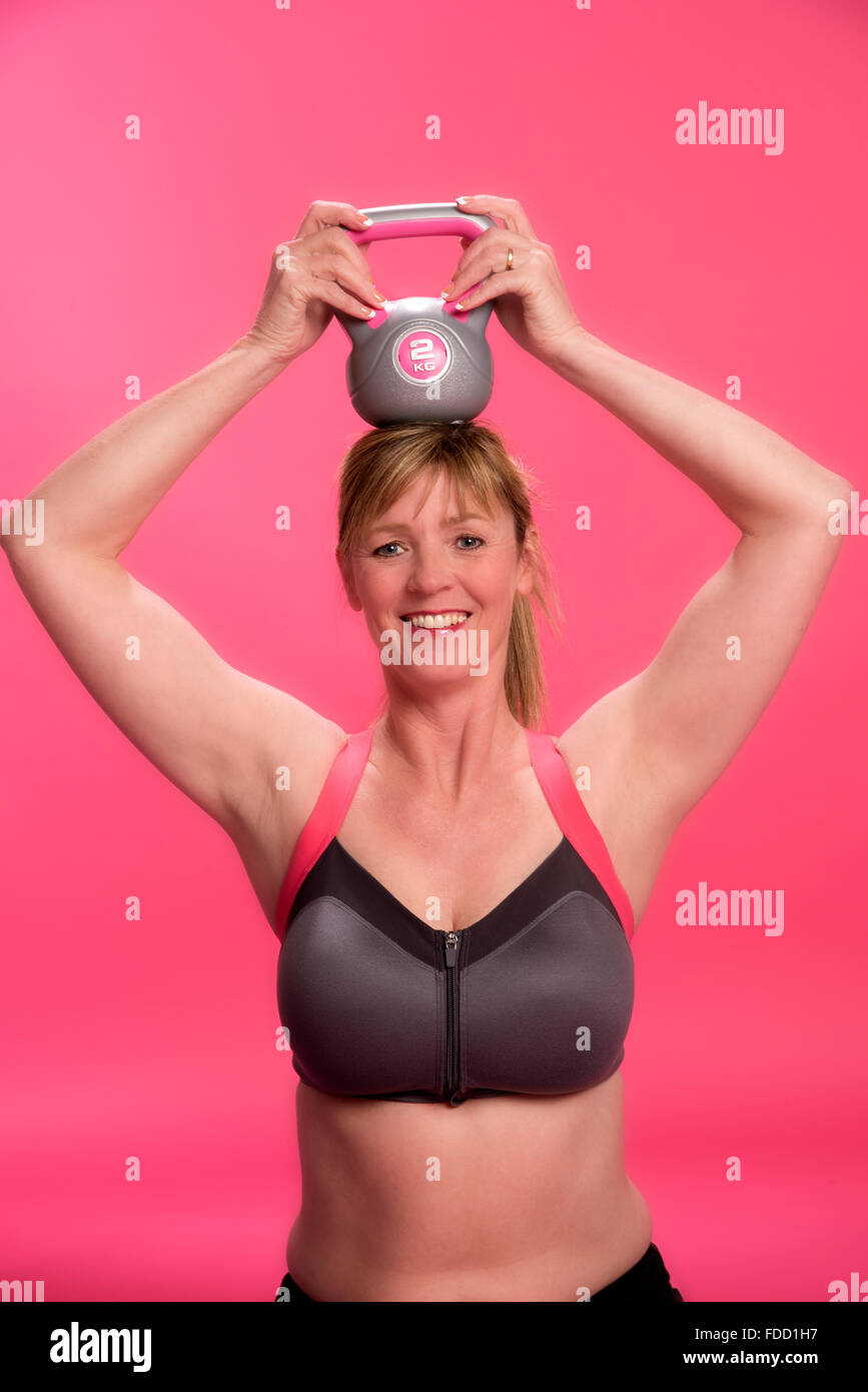 Donna che indossa reggiseno sportivo esercizio con un bollitore bell Foto Stock
