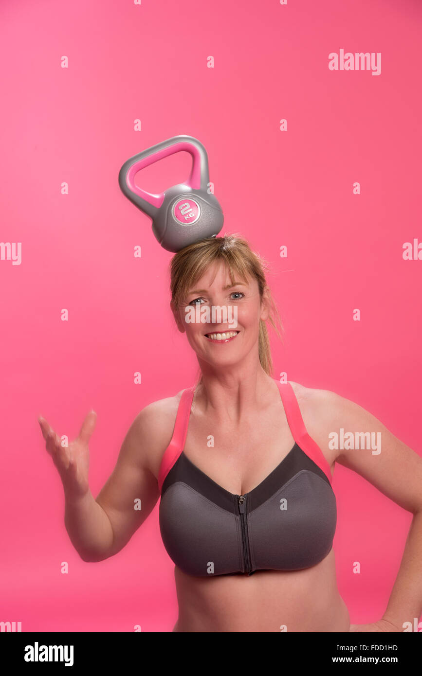 Donna che indossa reggiseno sportivo esercizio con un bollitore bell Foto Stock