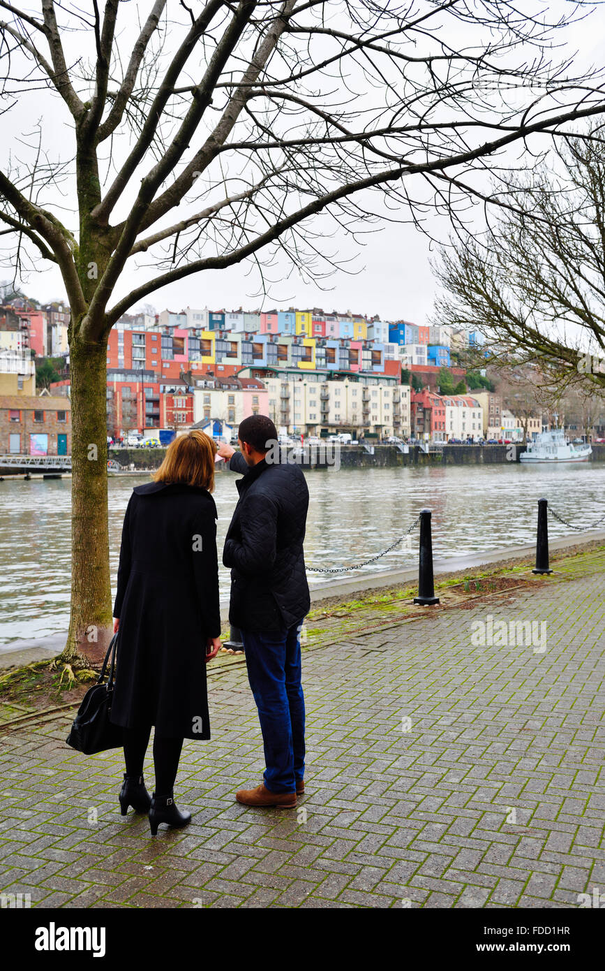 Uomo e donna che guarda oltre il Bristol Floating Harbour a case colorate in Hotwells e Clifton legno Foto Stock