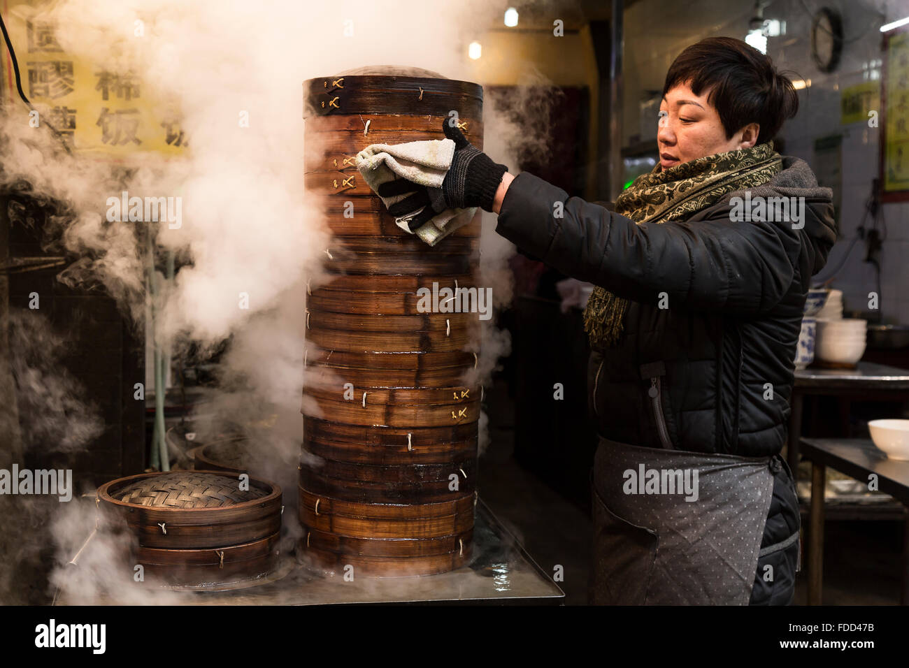 Xi'an, Cina. Gennaio 2016 - una signora cottura gnocchi di patate al vapore in un mercato al Quartiere Musulmano. Foto Stock