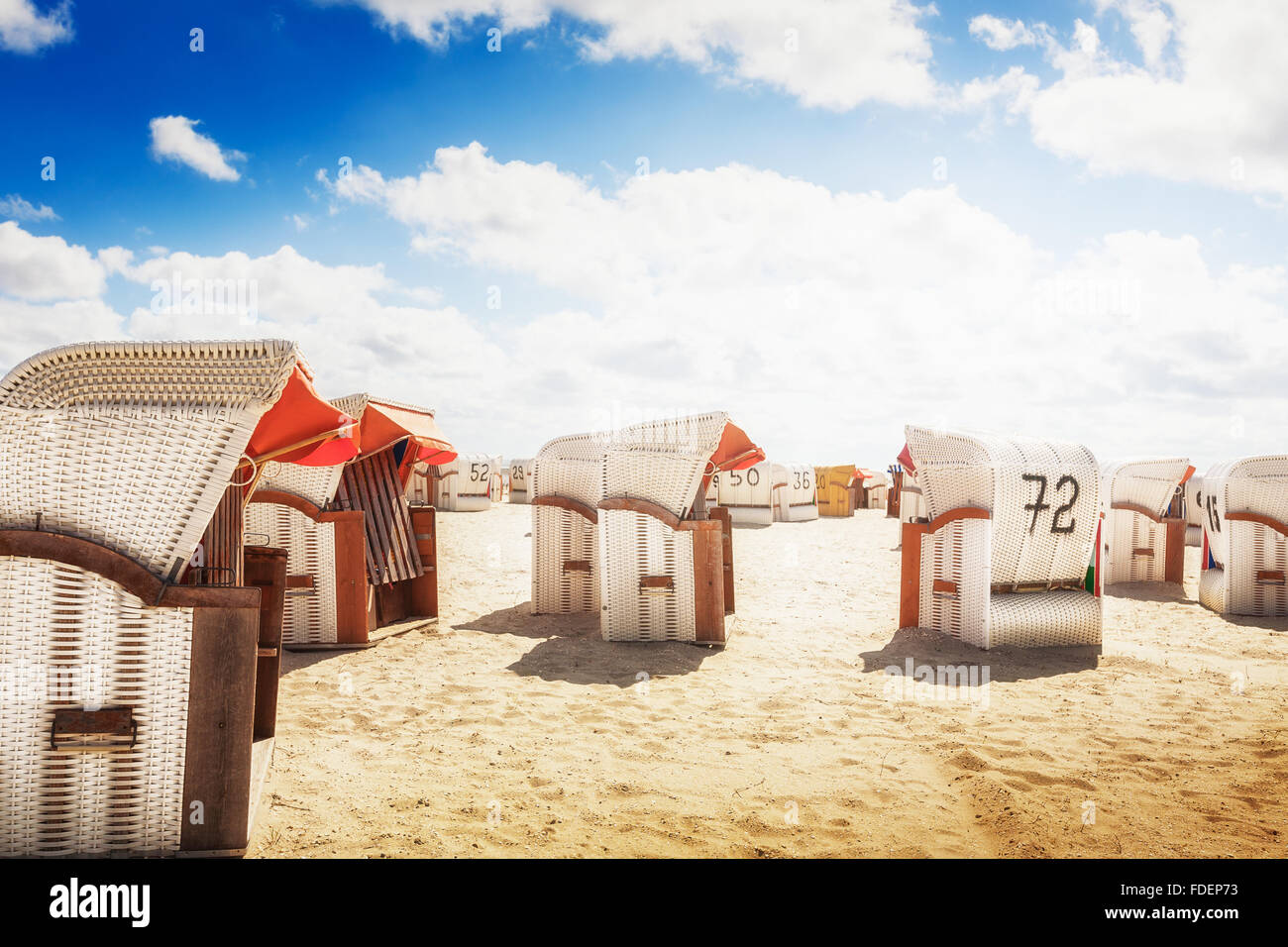 Con cappuccio bianco sedie a sdraio sulla spiaggia di sabbia. La luce del sole e il blu cielo nuvoloso. Sfondo di vacanza. Costa del Mare del Nord, meta di viaggio Foto Stock