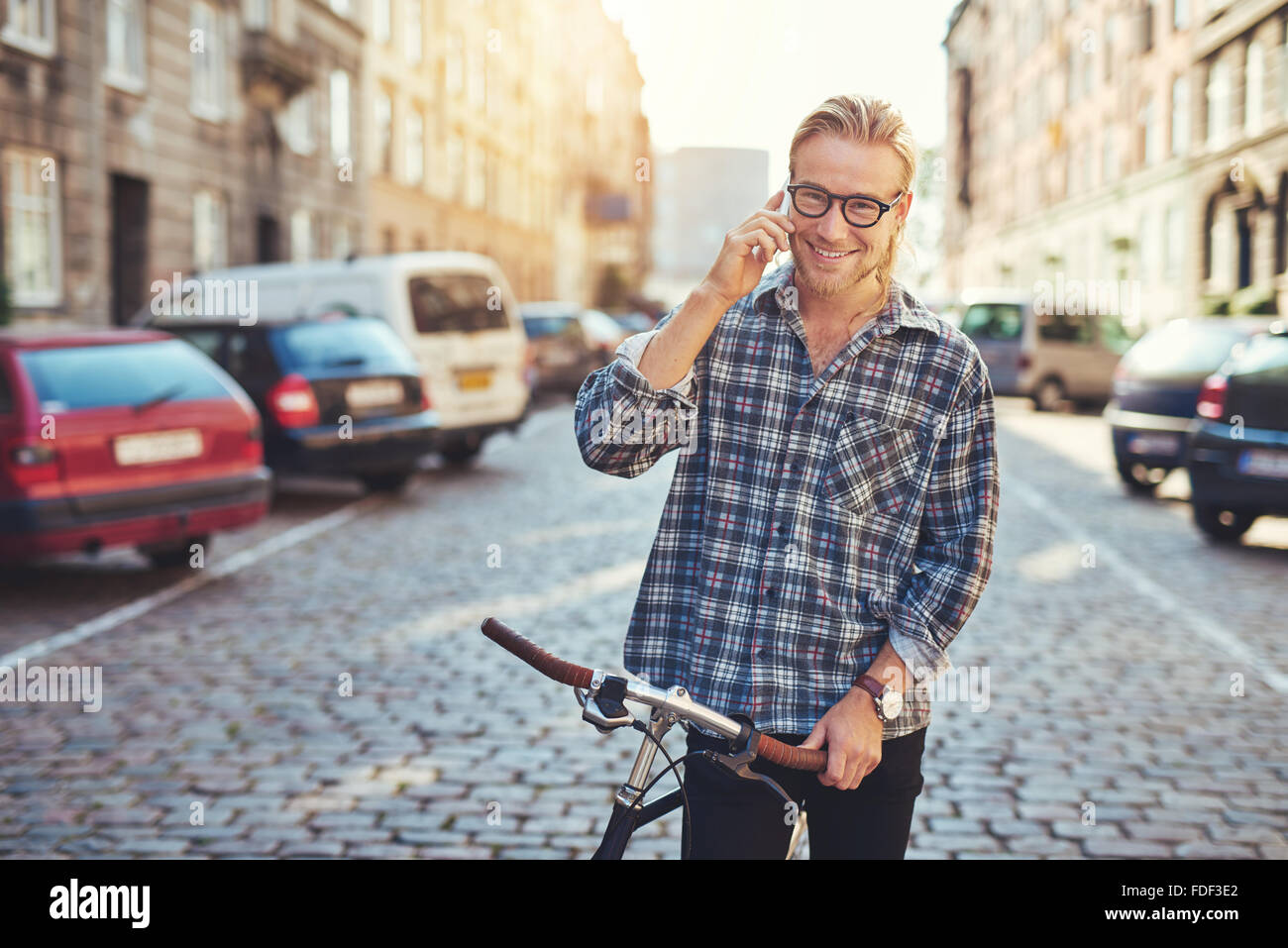 Felice giovane uomo nella città, parlando sul suo cellulare mentre sorridente Foto Stock