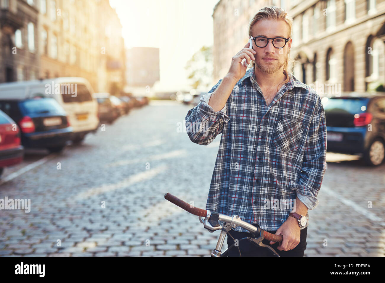 Un ritratto di un bel giovane uomo che parla sul suo cellulare nella città Foto Stock