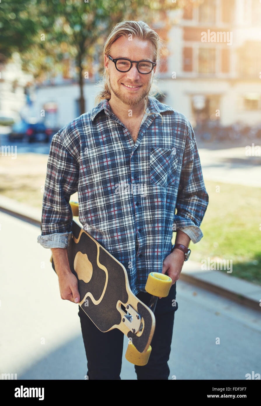 Ritratto di giovane uomo, lo stile di vita della città, portando il suo skateboard Foto Stock