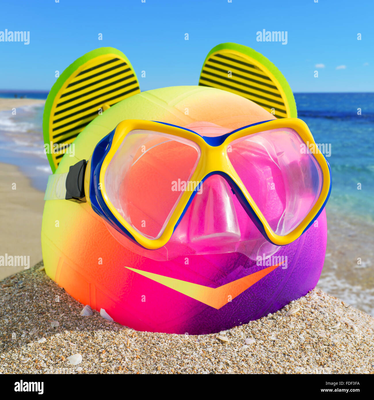 Sorridente piccolo uomo di spiaggia accessori. Sfera, flip-flop e maschera subacquea sulla spiaggia contro il blu del mare e del cielo. Foto Stock