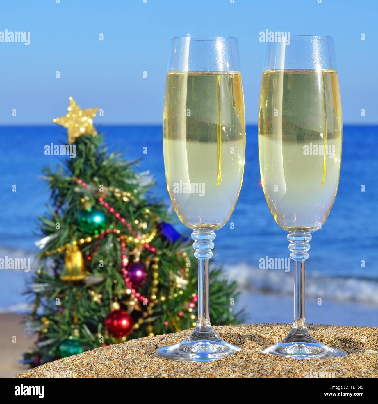 Seascape con bicchieri di champagne e un albero di Natale sulla spiaggia contro il blu del mare e del cielo Foto Stock