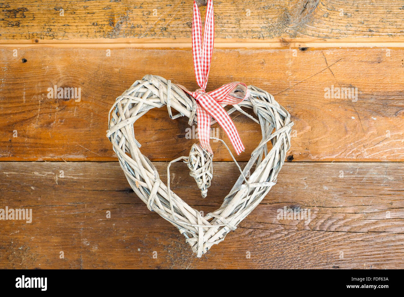 Home reso cuore costruita con paglia, appeso alla parete in legno per festeggiare San Valentino. Foto Stock