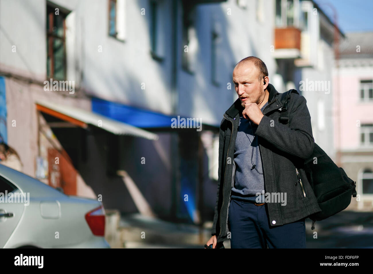 Brutale fotografo di strada con la fotocamera in mano a passeggiare per le strade delle città, parlando su un walkie-talkie vivavoce. Foto Stock