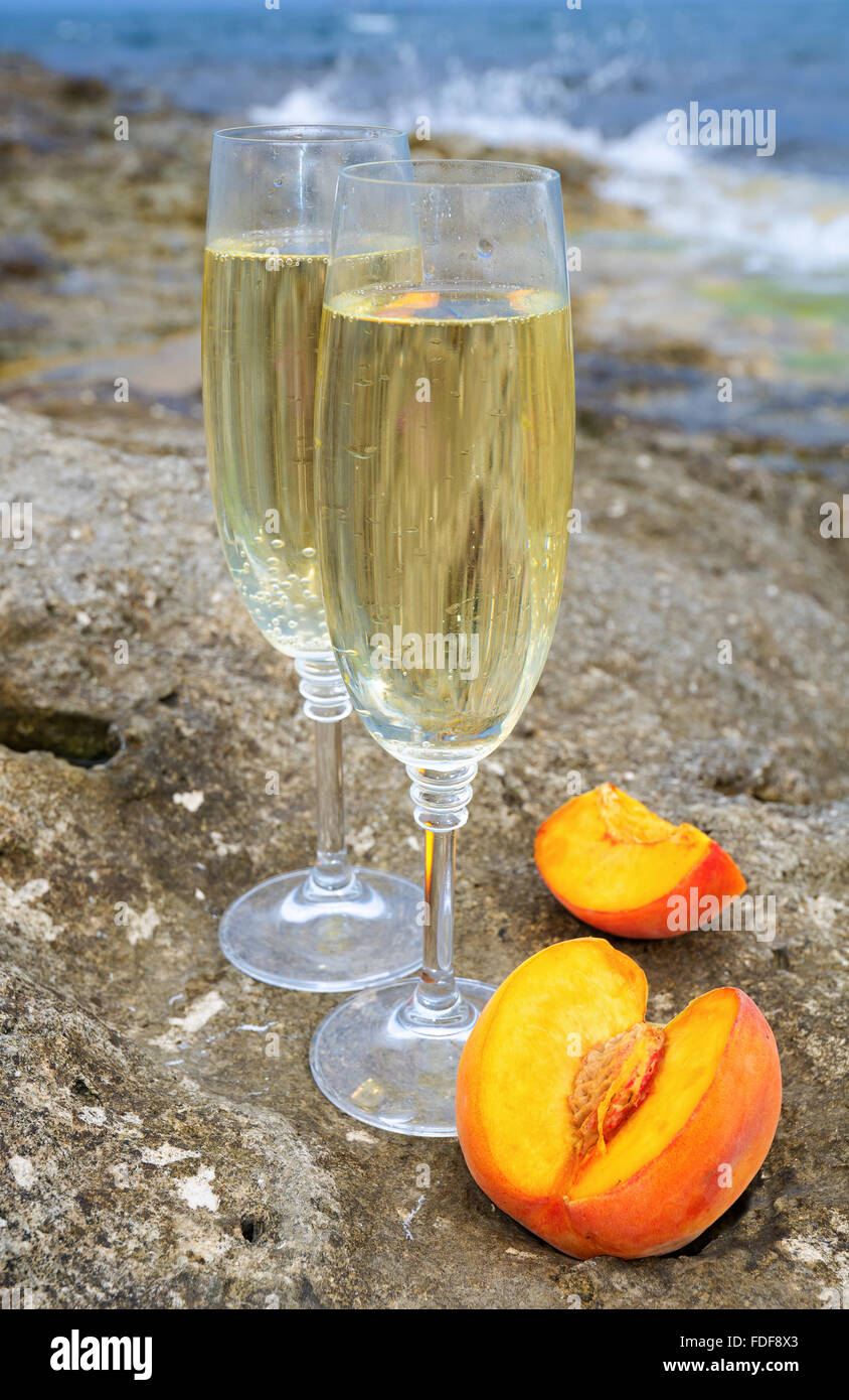 Occhiali con champagne e pesca sulle rocce in riva al mare Foto Stock