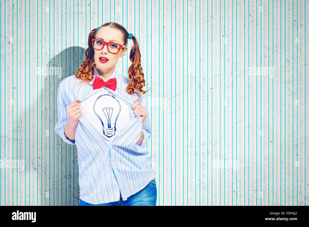 Giovane donna che agisce come super eroe con illustrazione della lampadina sul petto Foto Stock