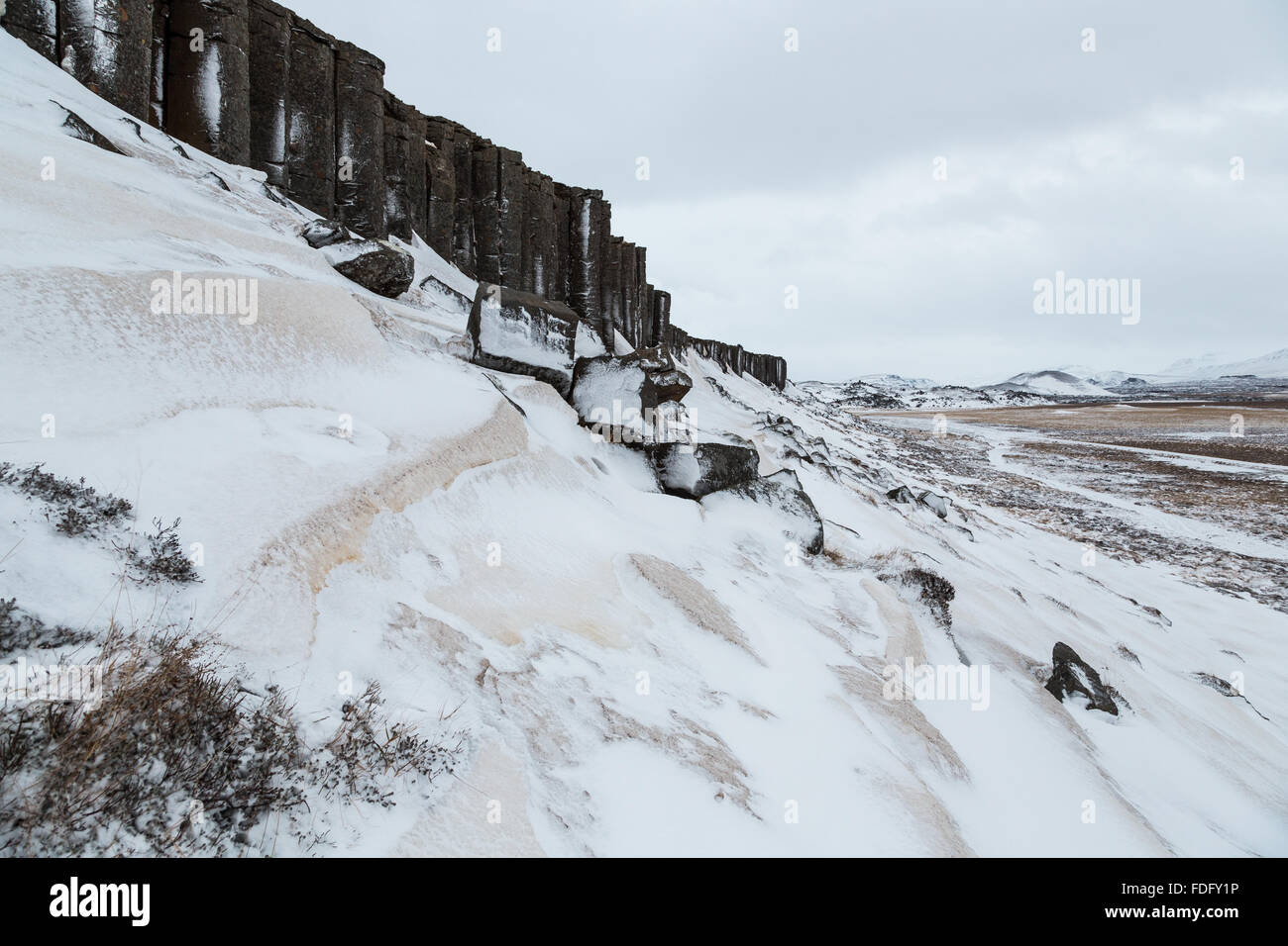 Le Scogliere Gerðuberg in western Islanda formano una linea retta di forma esagonale colonne di basalto stretching attraverso il paesaggio innevato. Foto Stock