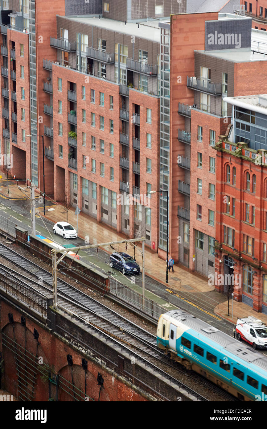 Arriva il treno lascia Manchester Oxford Road per eseguire in parallelo con Whitworth Street passato la Hacienda edificio viaggiatori di viaggio Foto Stock