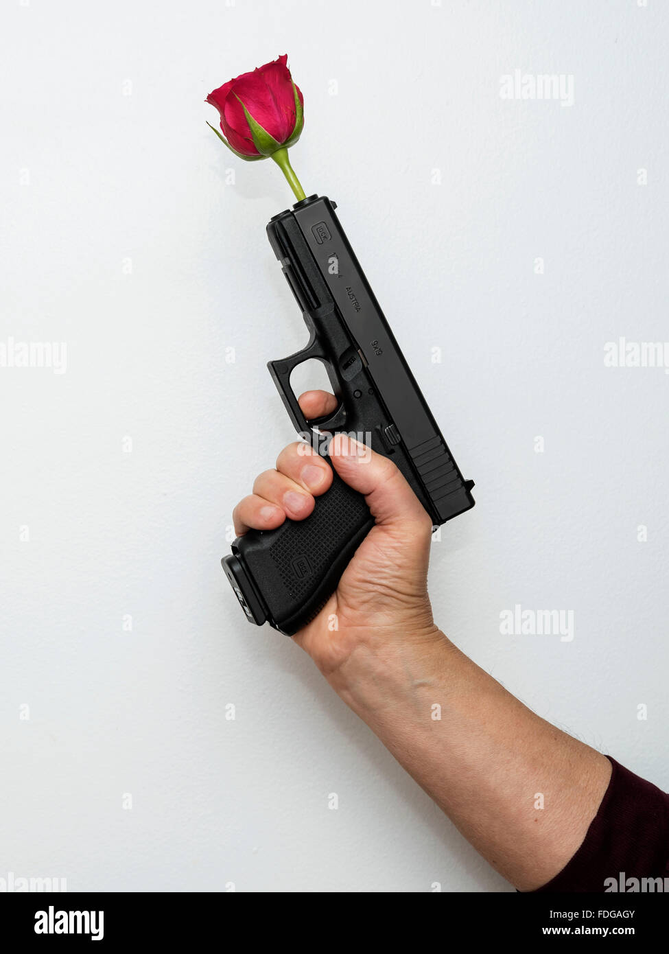 Mano con la pistola con una rosa rossa in canna come un simbolo di pace e di amicizia Foto Stock