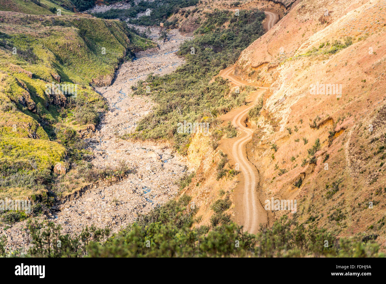 Vuoto su strada sterrata verso il basso di avvolgimento di una montagna in Sani Pass, tra il Sudafrica e il Lesotho. Foto Stock