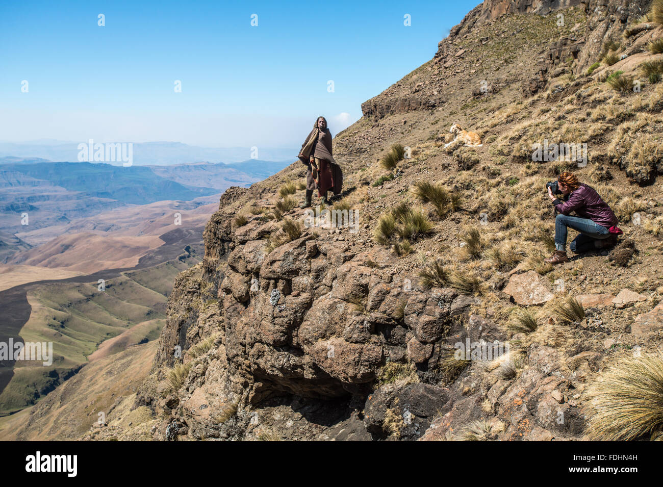 Ragazza turistica fotografando un pastore locale sul lato di una montagna in Lesotho, Africa Foto Stock