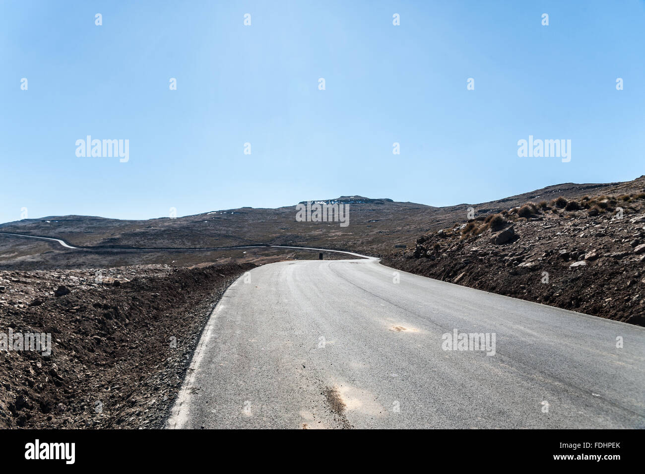 Strada asfaltata avvolgimento attorno il terreno roccioso del Lesotho, Africa Foto Stock