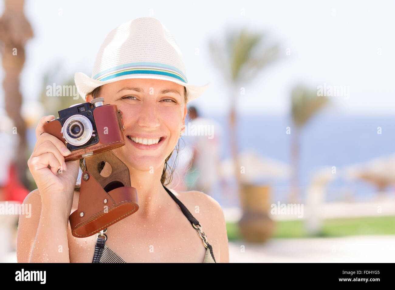 Giovane donna felice con i denti sani divertendosi con la vecchia foto fotocamera in estate vacanze in spiaggia. Foto Stock