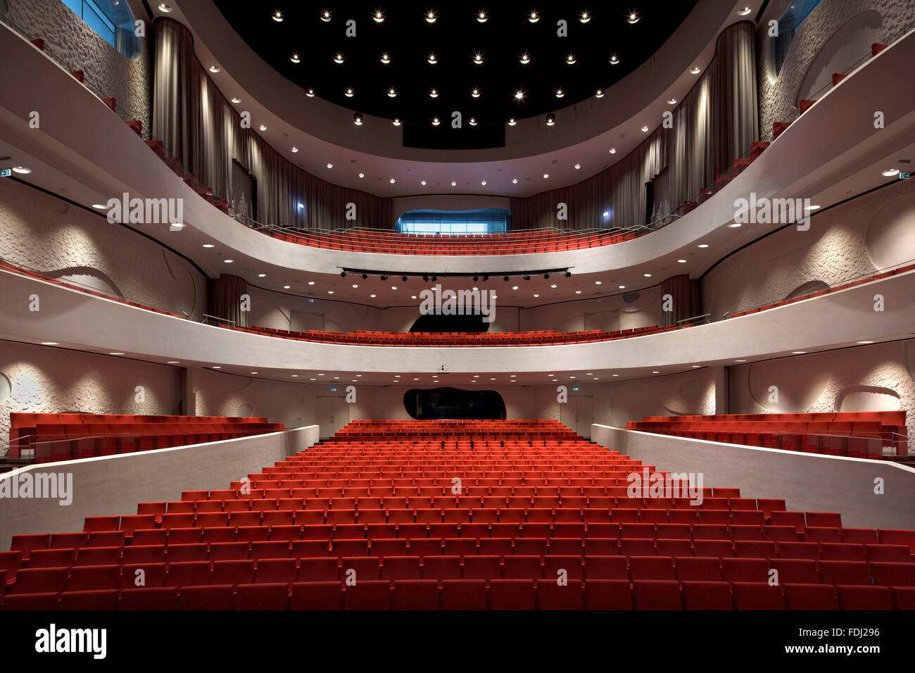 Sala principale con posti a sedere rossi contro la curvatura pareti bianche e balconi. Musikkens Hus Aalborg, Aalborg, Danimarca. Architetto: Coop Foto Stock